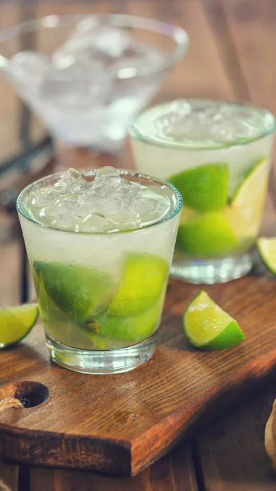 Bicchieri trasparenti con caipirinha, ghiaccio e lime